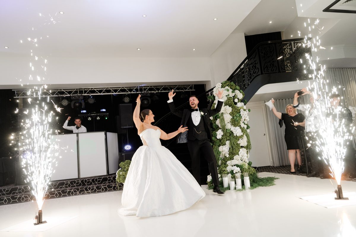 Bride and groom entering under indoor sparks